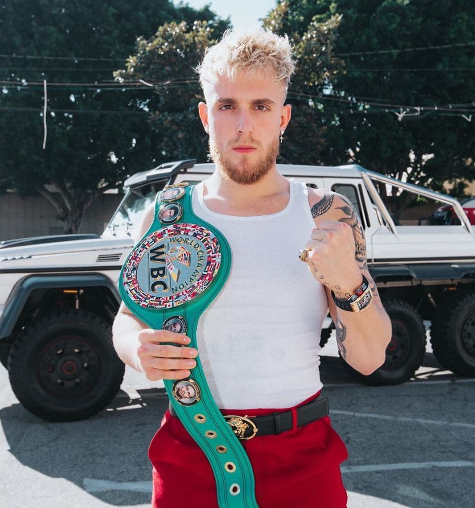 Jake Paul poses with a boxing championship belt.