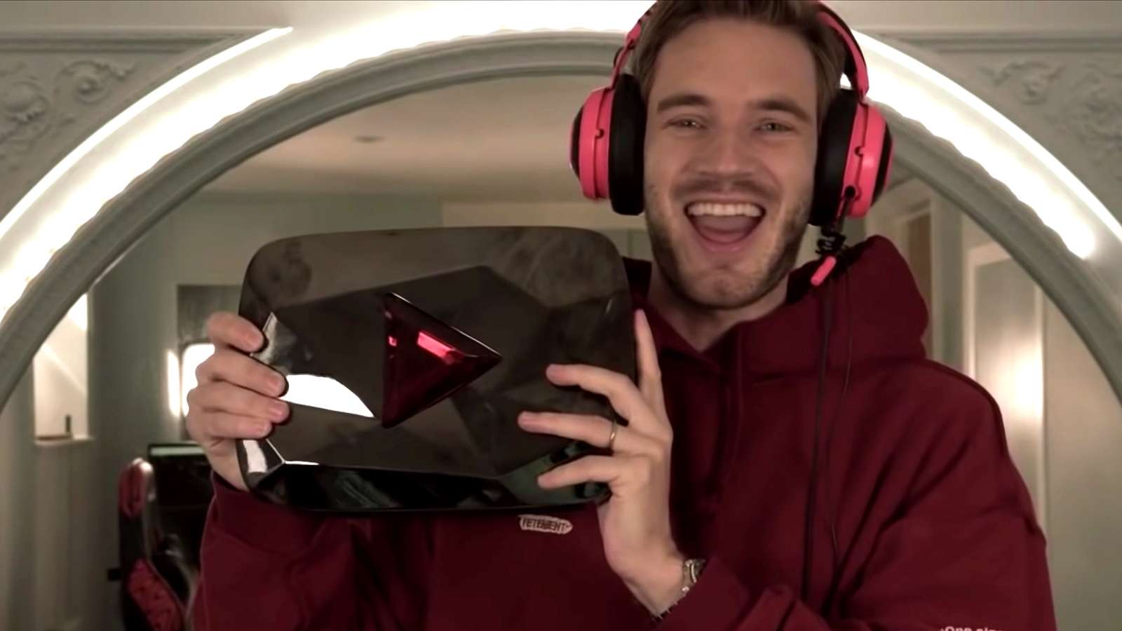 PewDiePie holding his 100 million subsrcibers reward in red hoody with headphones on