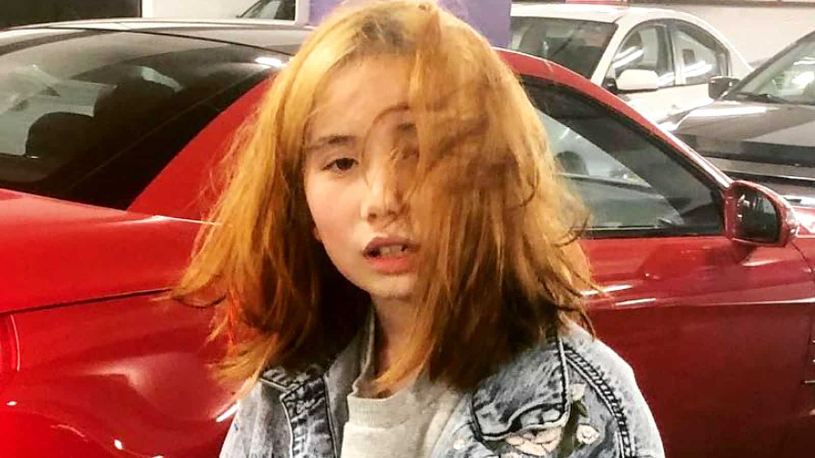 Lil Tay poses in front of a car
