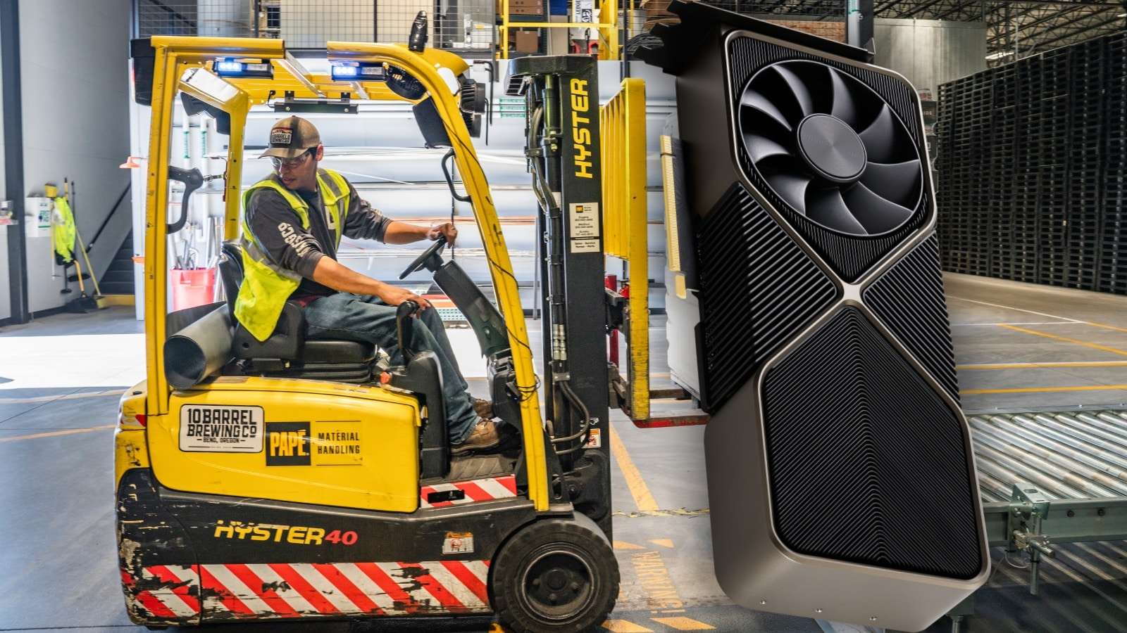 A graphics card enlarged to look like a factory worker is holding it up with a forklift.