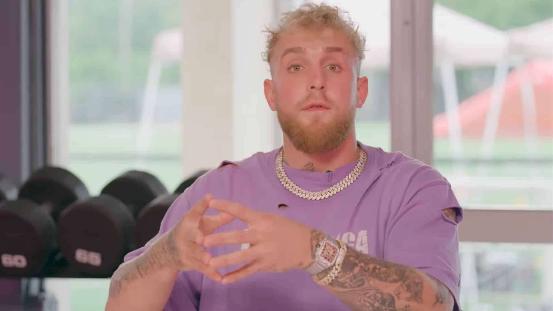 Jake Paul is violet shirt talking to camera with hands closed