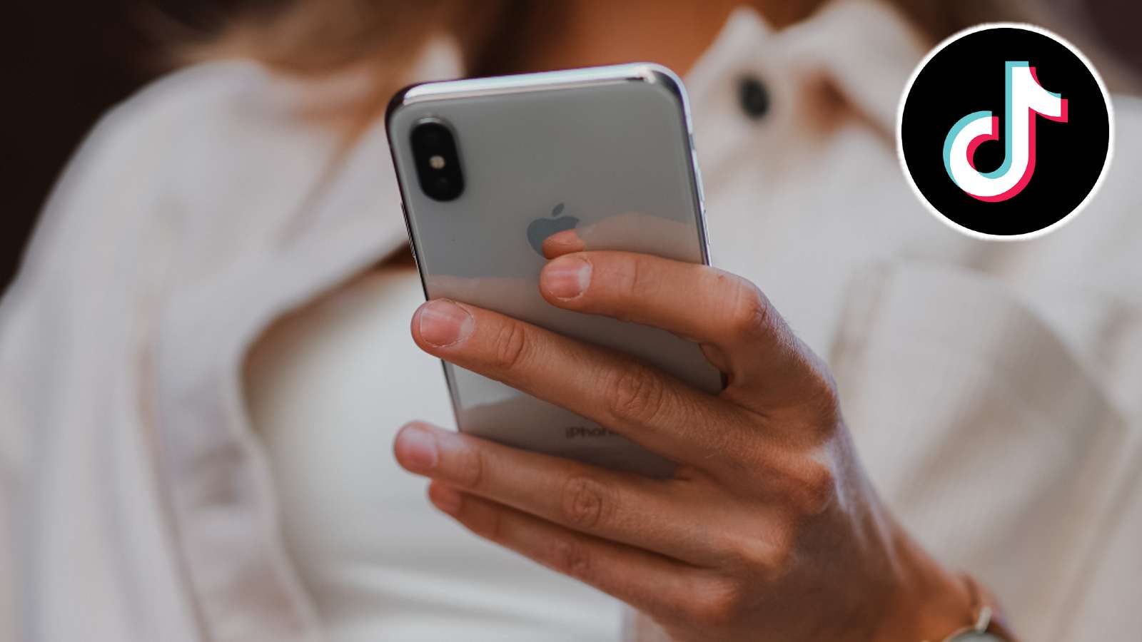 Woman holding a phone, along with the tiktok logo in the corner