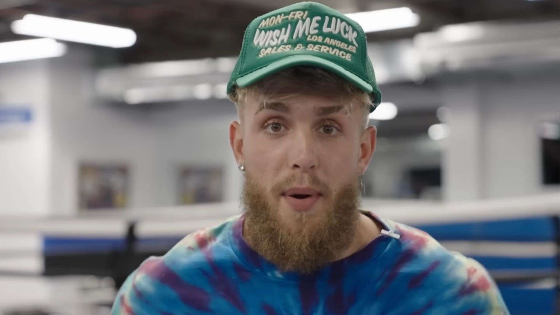 Jake Paul talking to camera in tye dye shirt and green hat