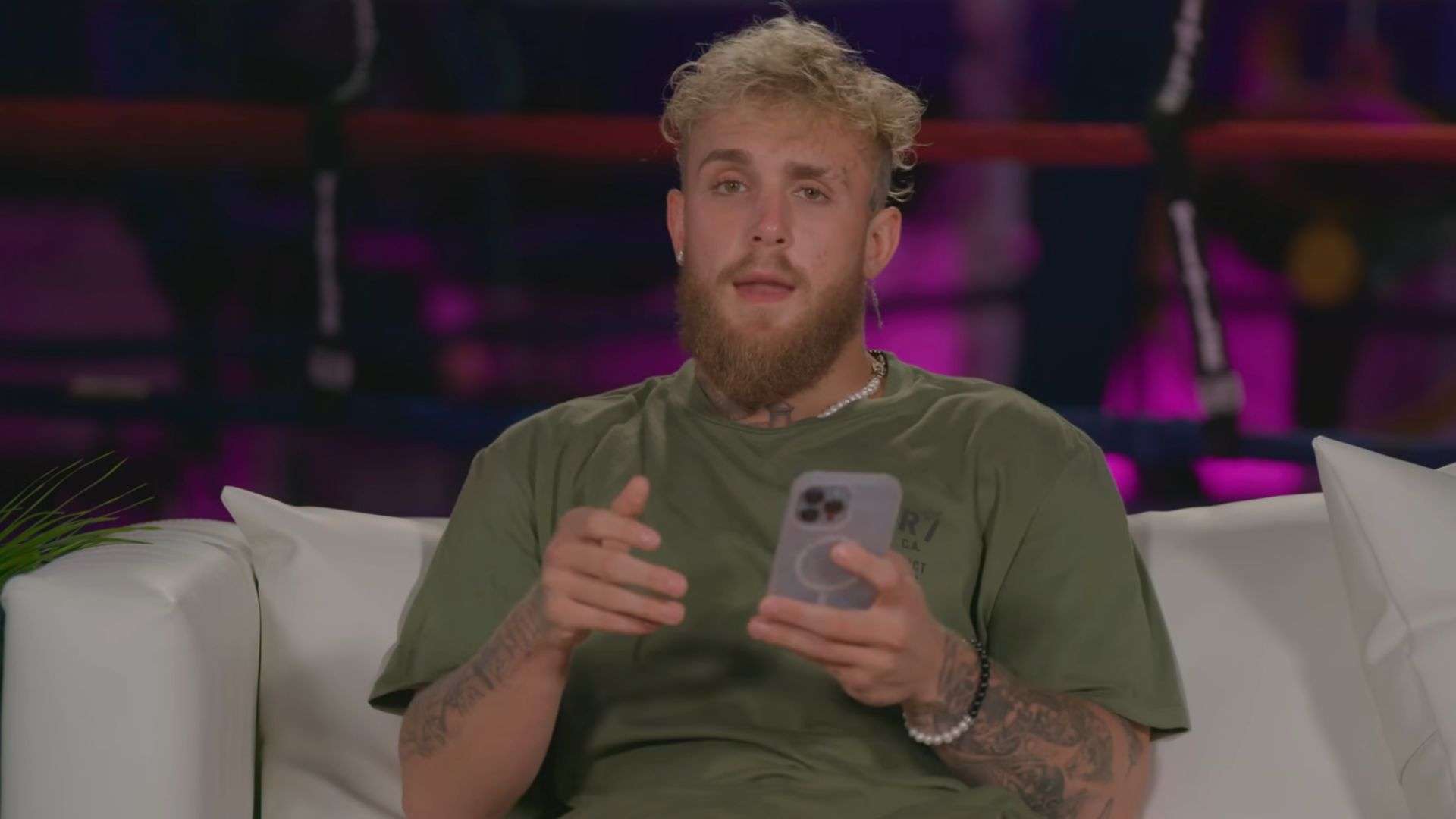 Jake Paul sat on couch talking to camera while holding phone