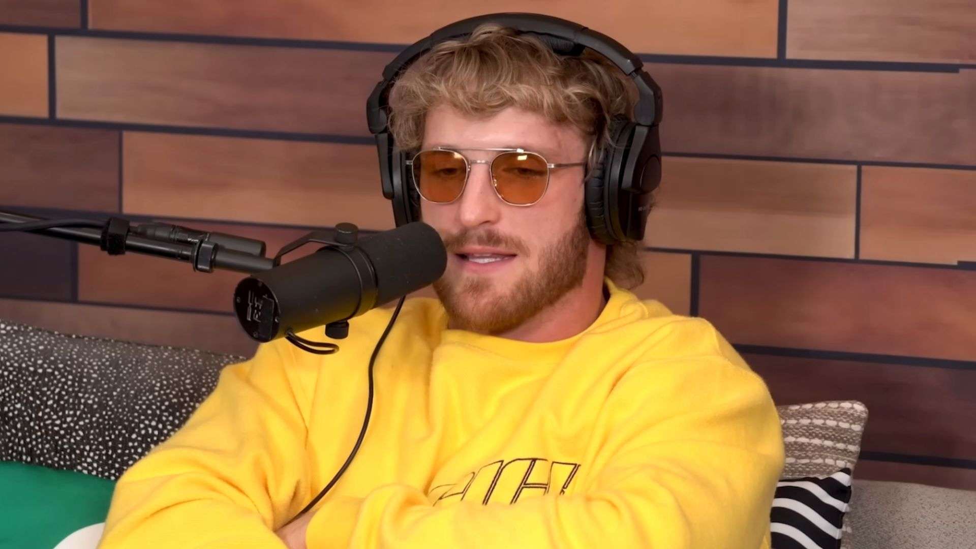 Logan Paul in yellow shirt and sunglasses talking to microphone