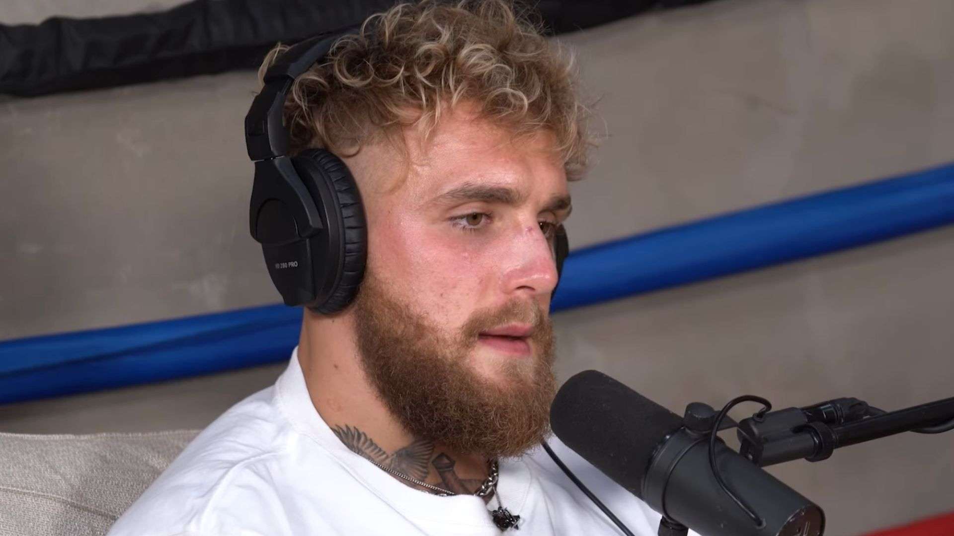 Jake Paul in white shirt with black eye talking into microphone