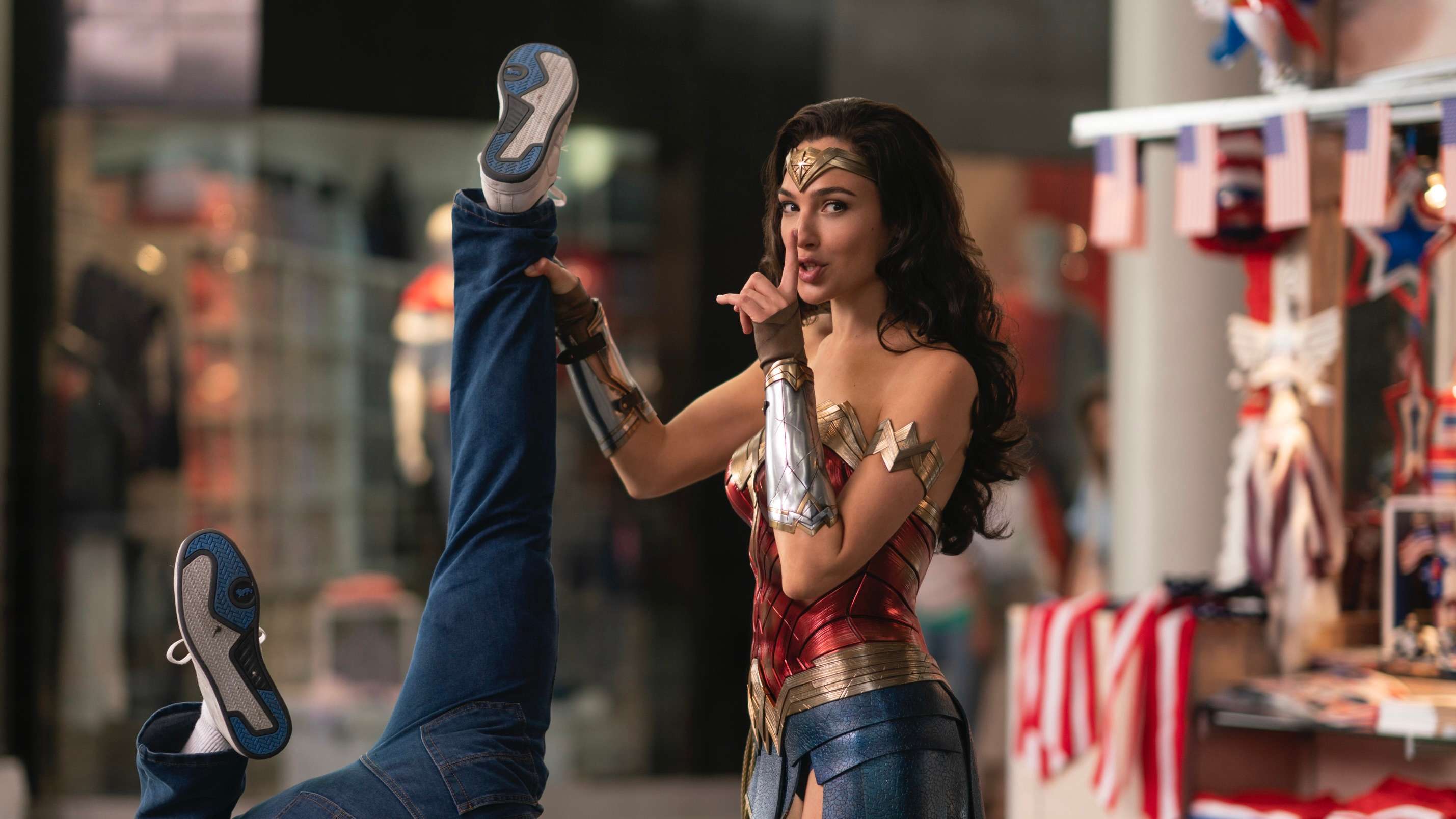 Wonder Woman holding a villain up by his feet.