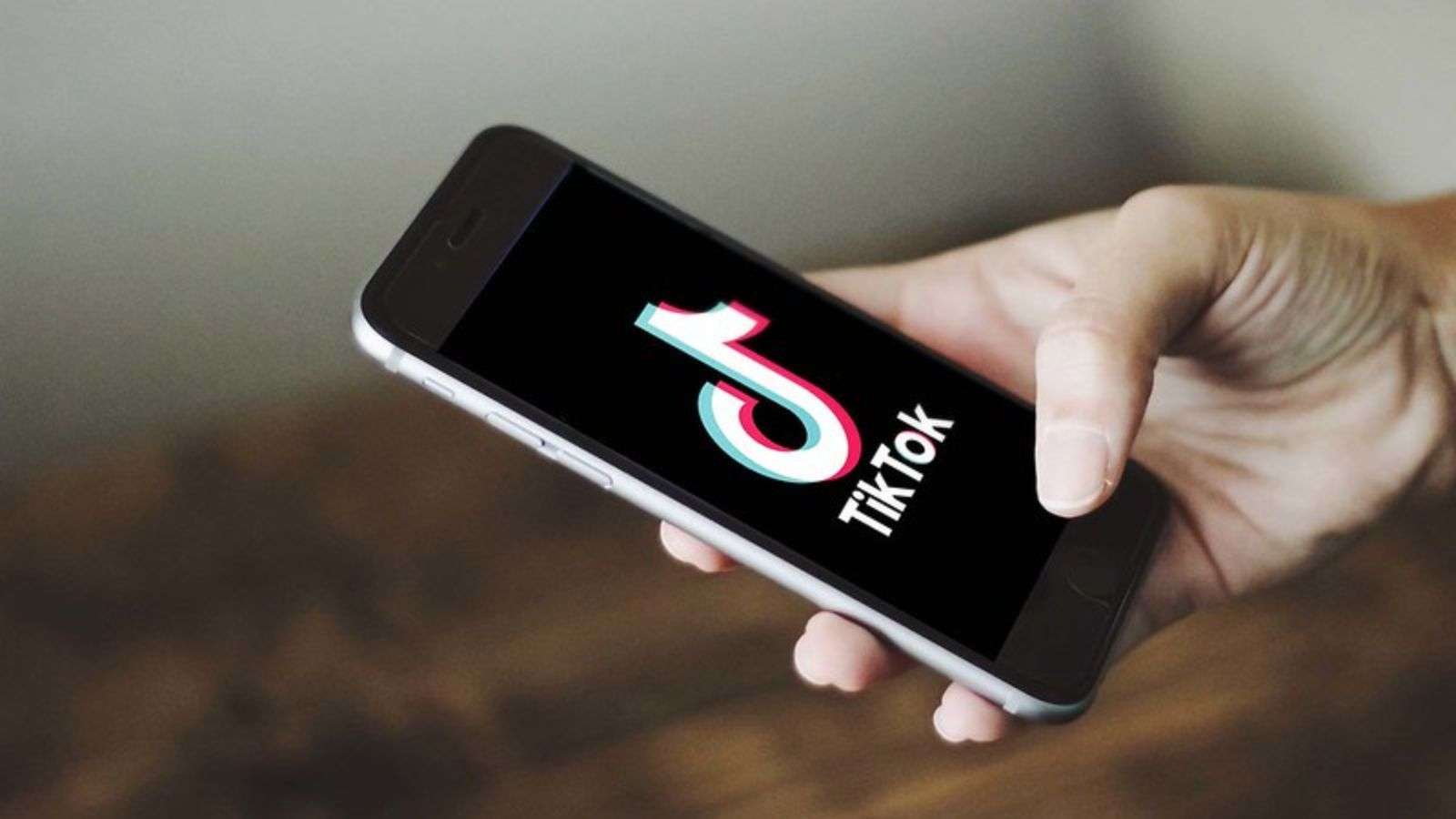 A hand holding a phone with the TikTok logo on the screen