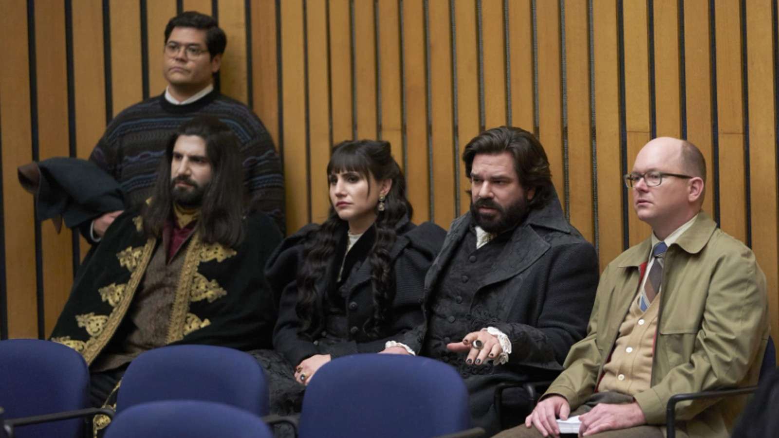The cast of What We Do in the Shadows attend a town meeting