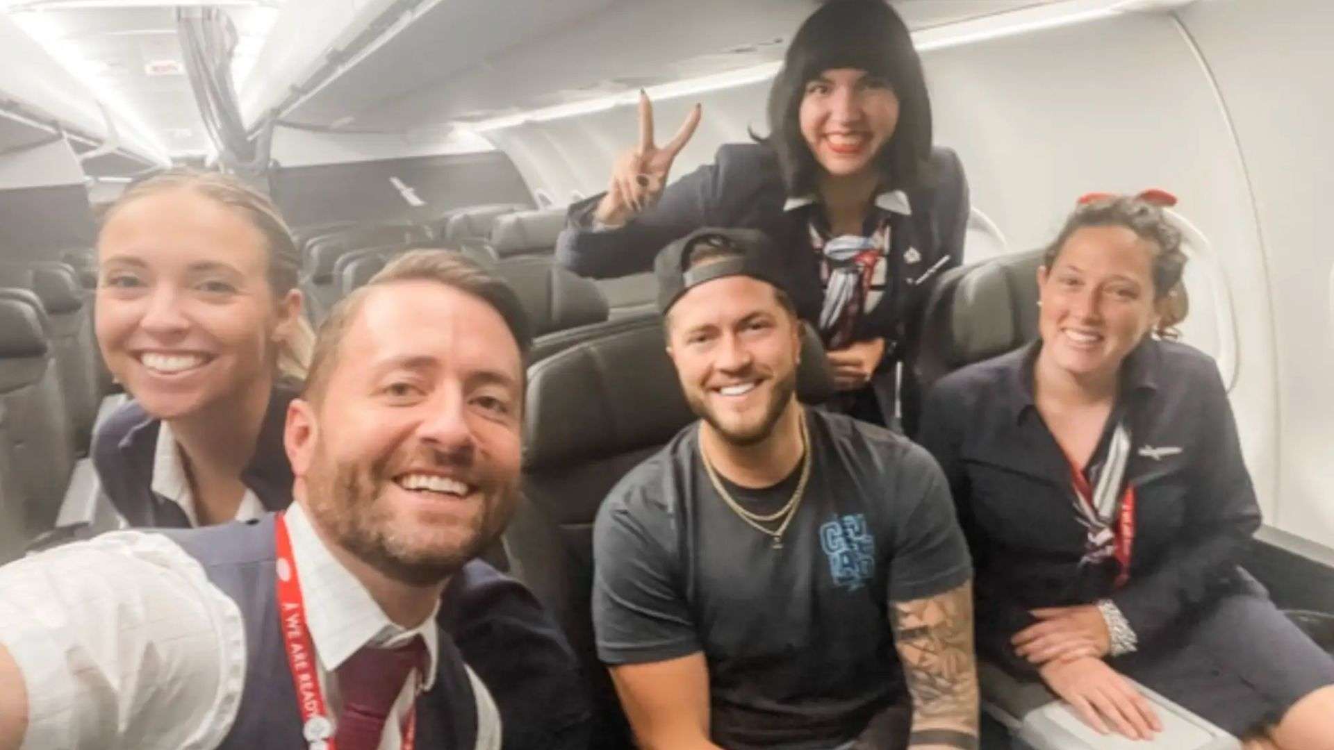 Man sat with cabin crew taking selfie on plane
