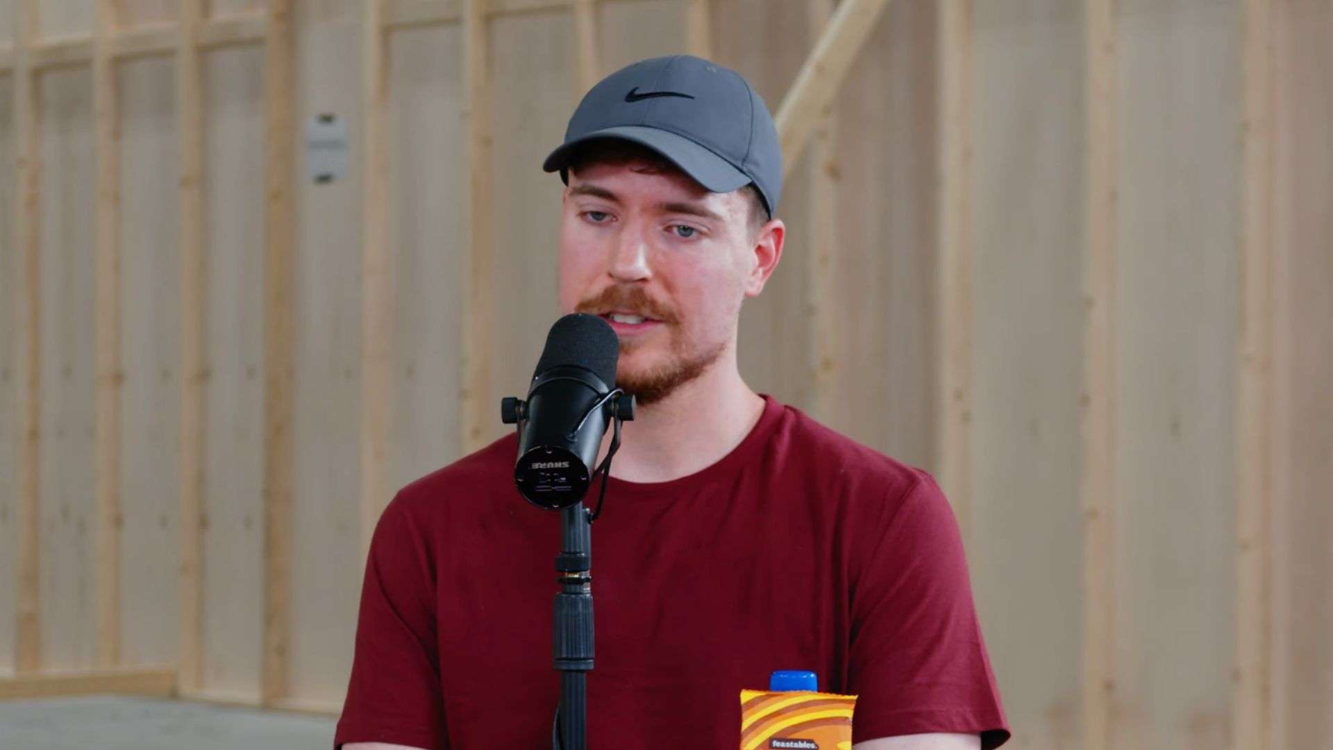 MrBeast talking into mic wearing red shirt and grey hat