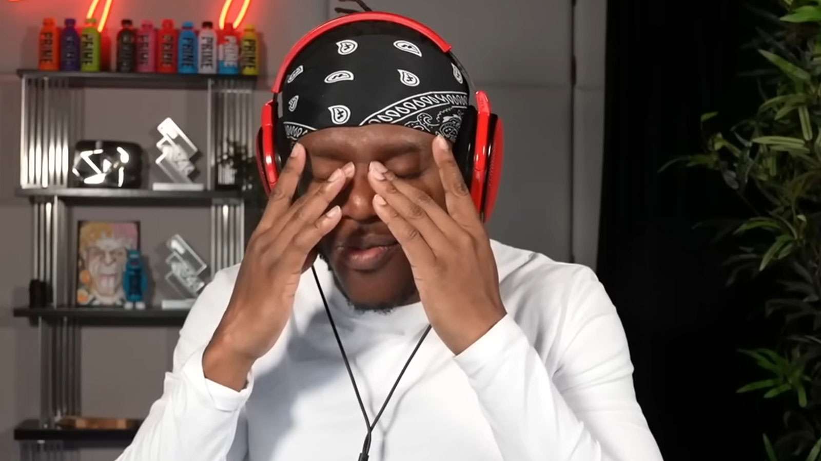KSI holding his head in his hands wearing white long sleeve