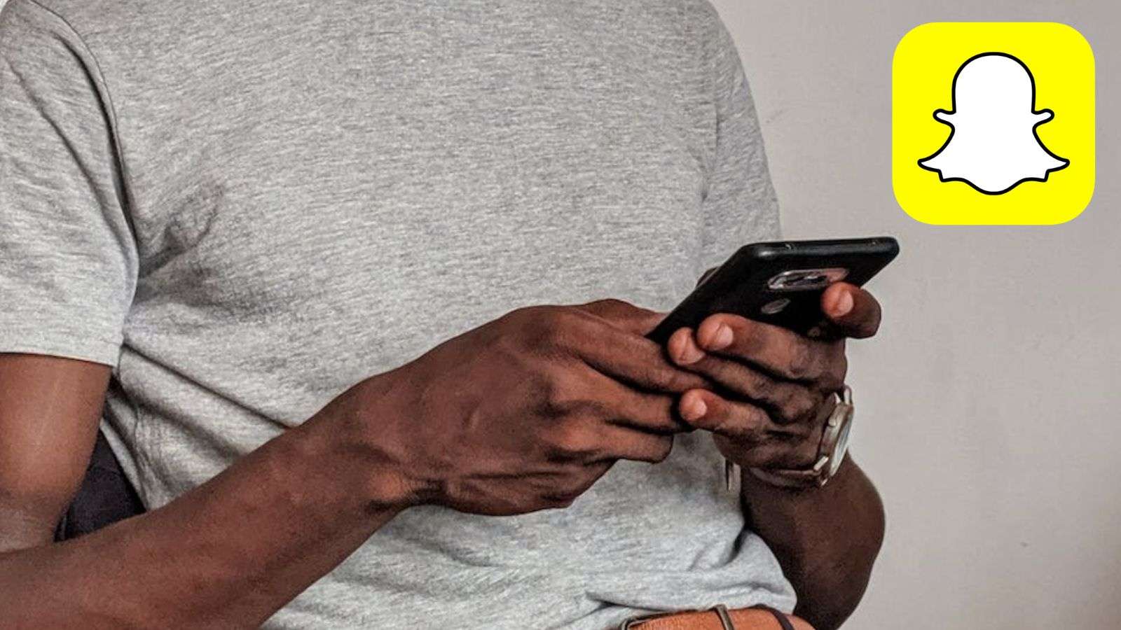 Snapchat logo next to person holding phone.