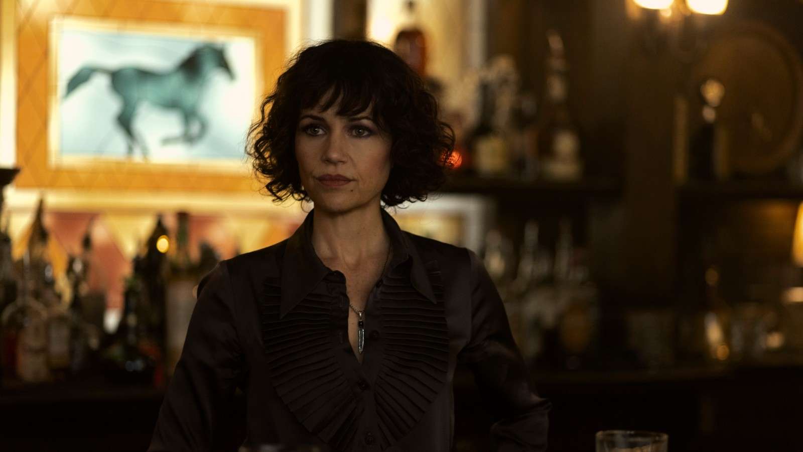 Carla Gugino standing in front of a bar in The Fall of the House of Usher