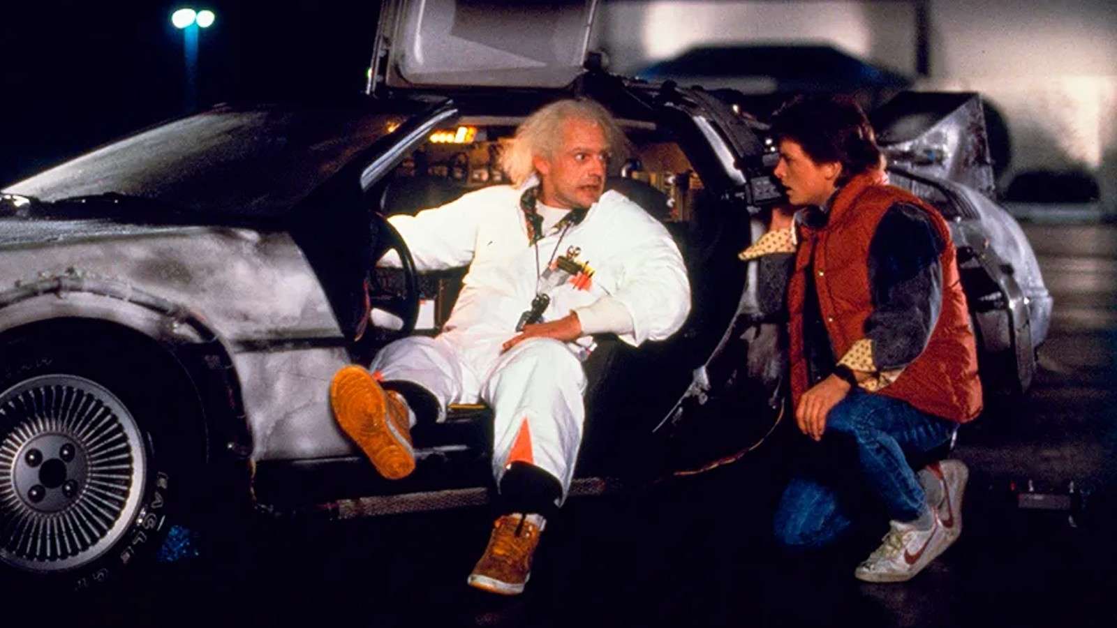 Doc Brown sitting in the Back to the Future DeLorean.