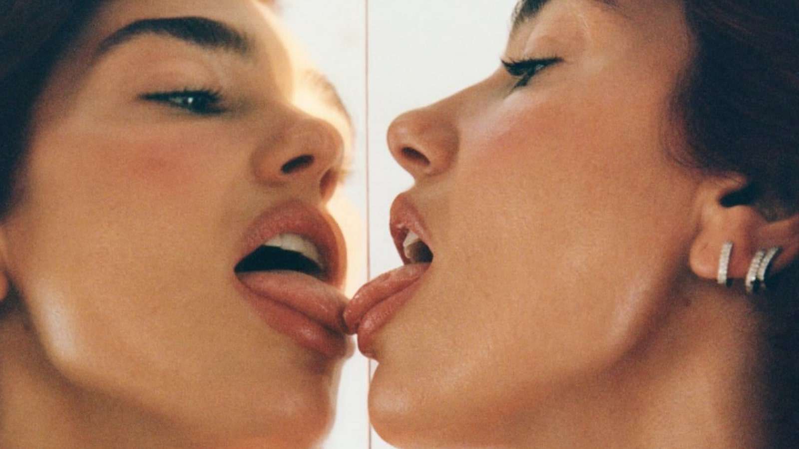 Pop singer Dua Lipa licking a mirror and a reflection of herself.