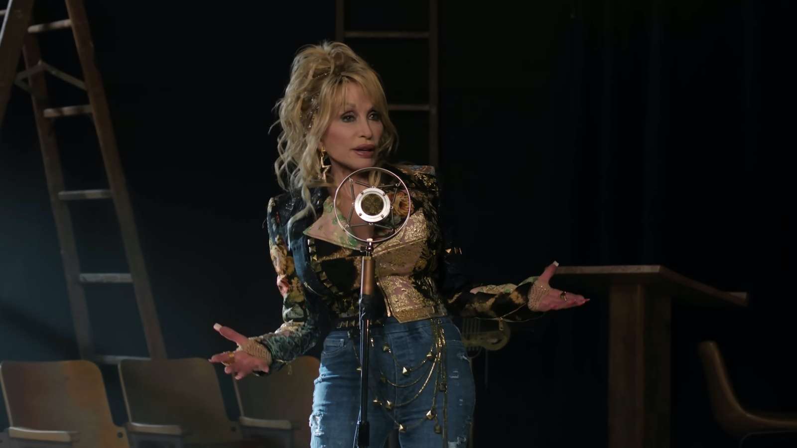 Doll Parton performing behind a microphone stand onstage