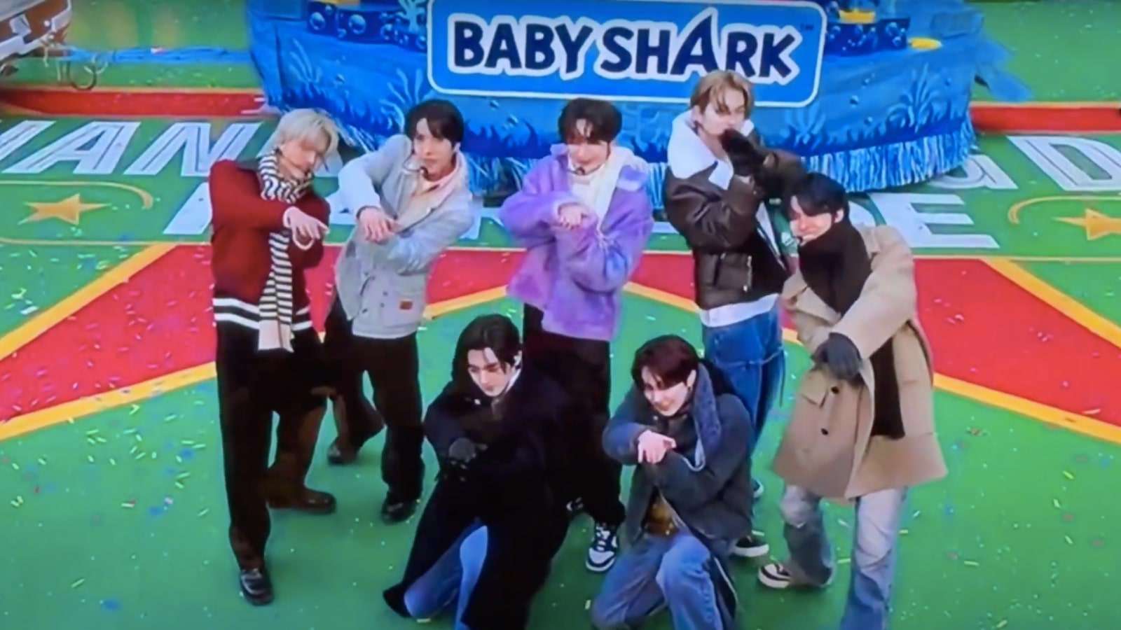 K-pop group Enhypen make shark gestures with their hands on a TV show