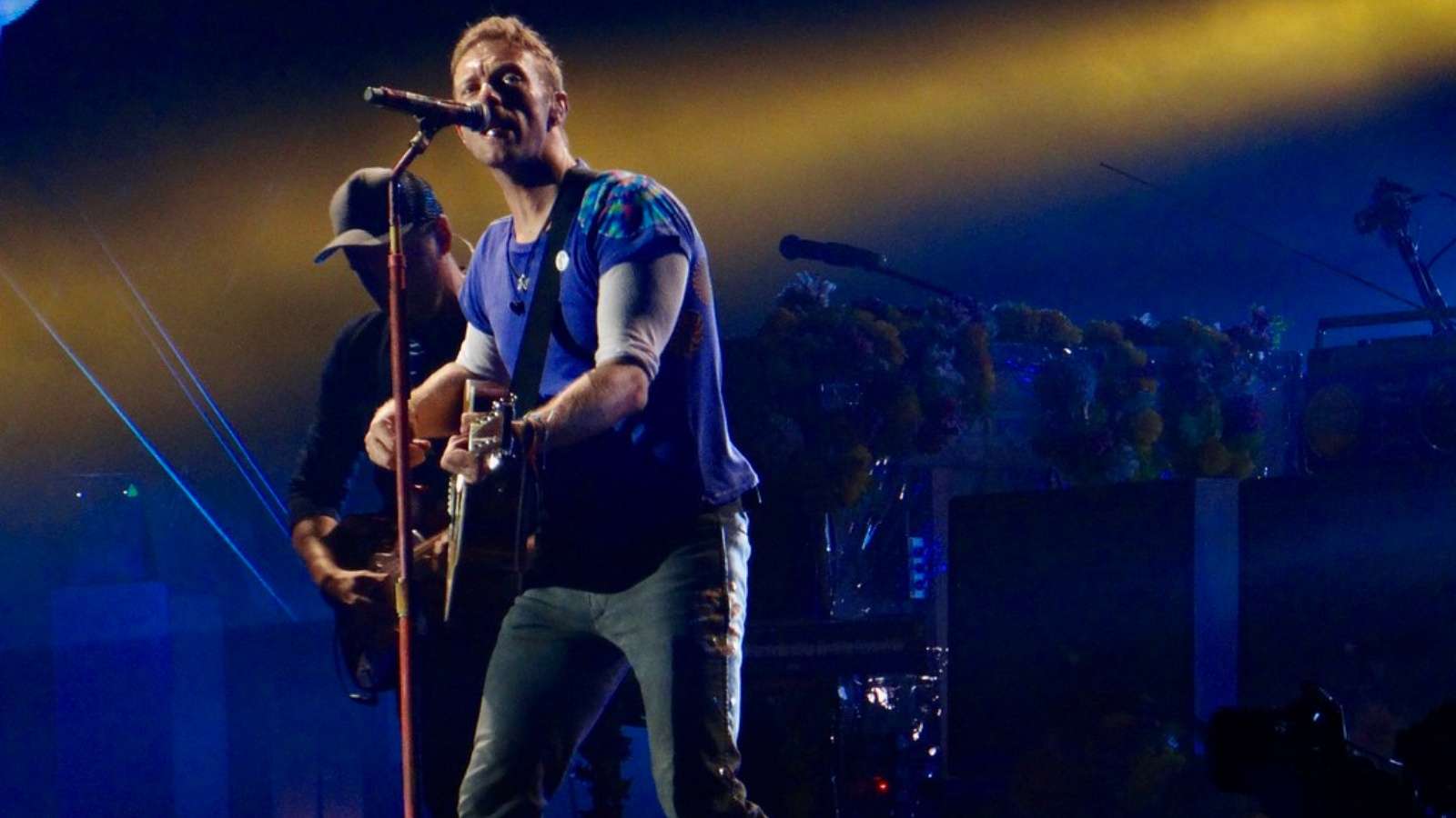 Coldplay's Chris Martin with a guitar playing at a concert onstage
