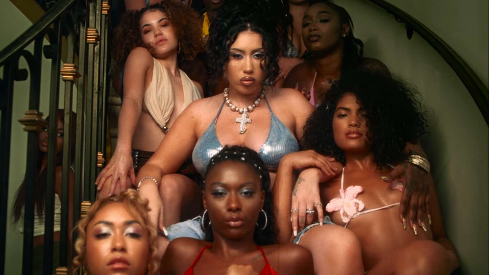 Kali Uchis sitting on a staircase surrounding by other women