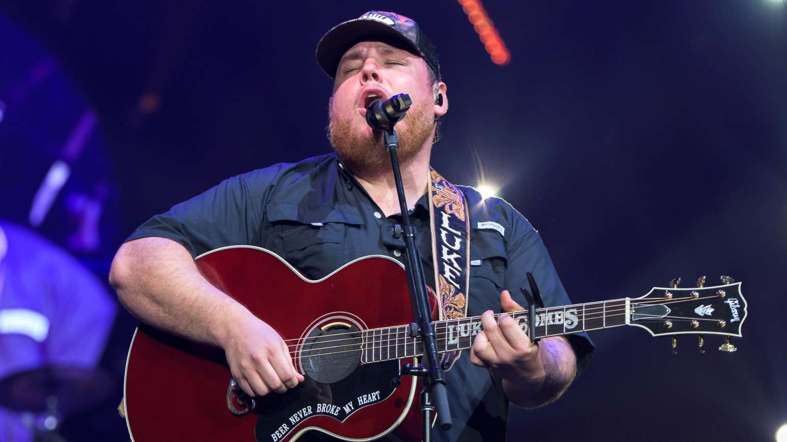 Luke Combs performing with an acoustic guitar onstage
