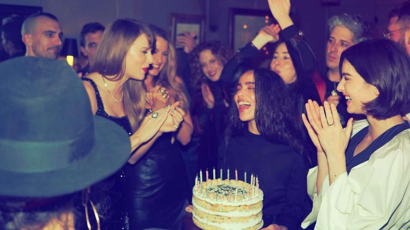 Taylor Swift and friends gathered around a birthday cake