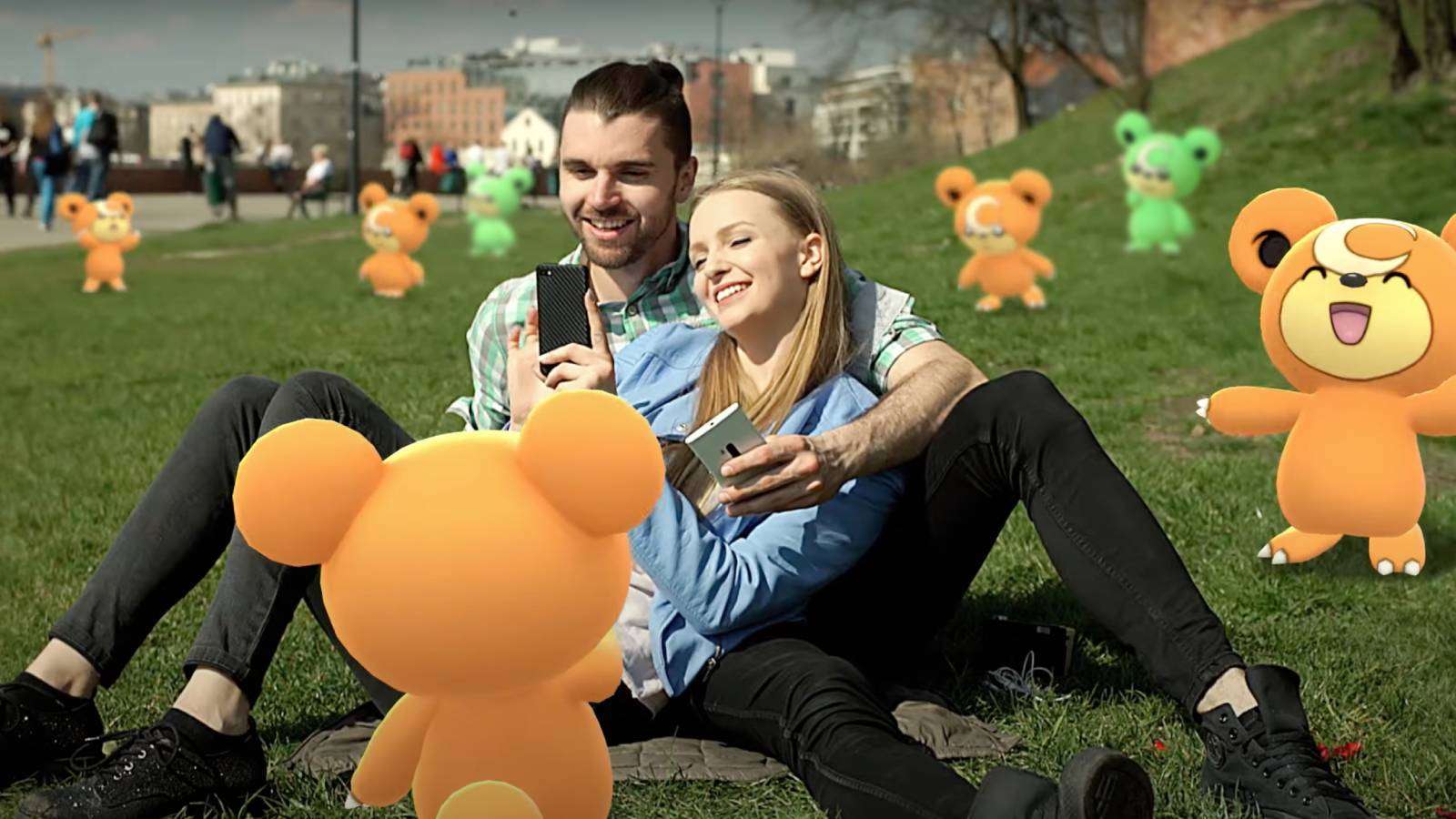Two Pokemon Go players sit in the grass, while Teddiursa appear around them, both regular and Shiny Pokemon