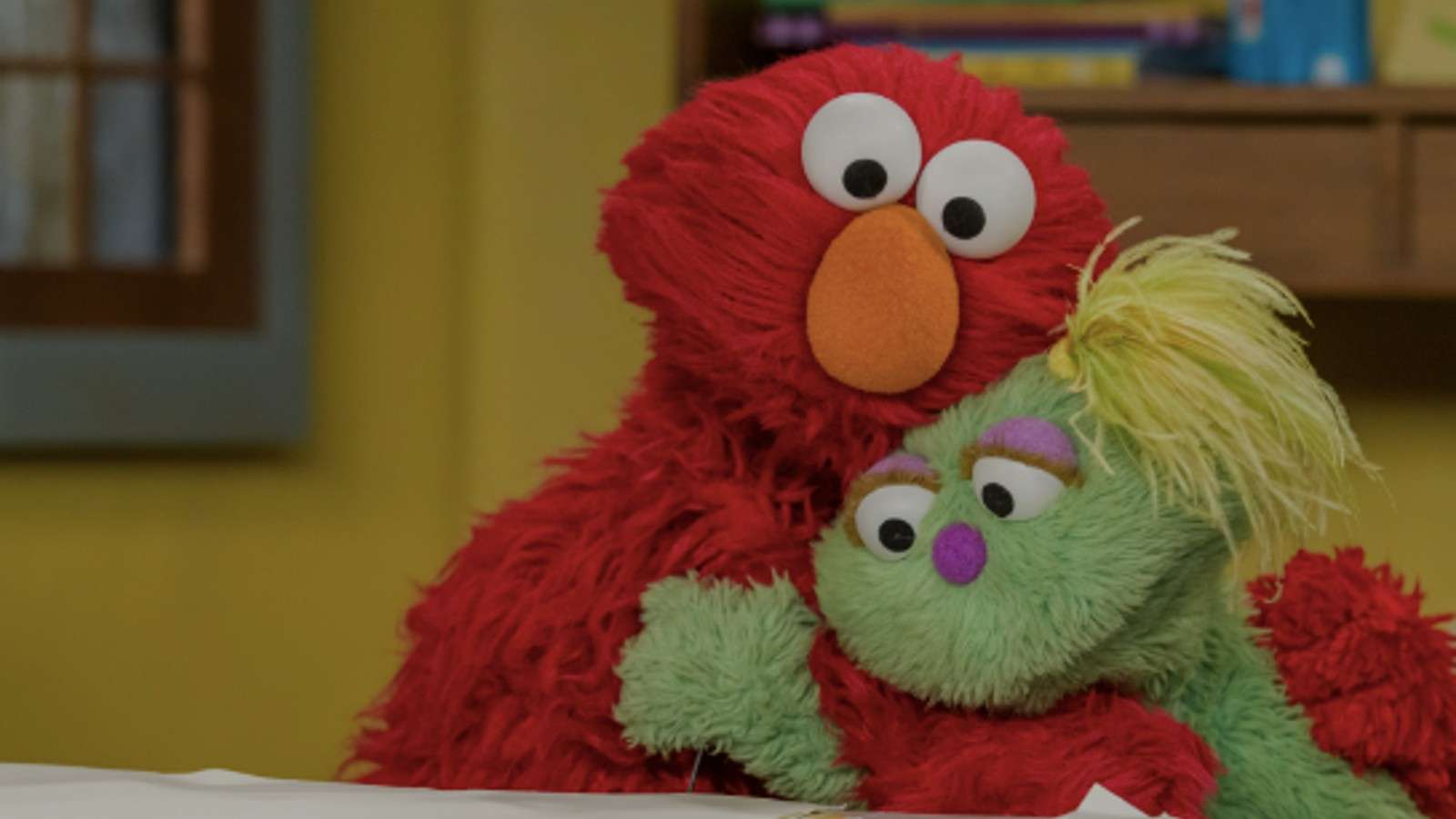 Elmo hugs his Muppet friend