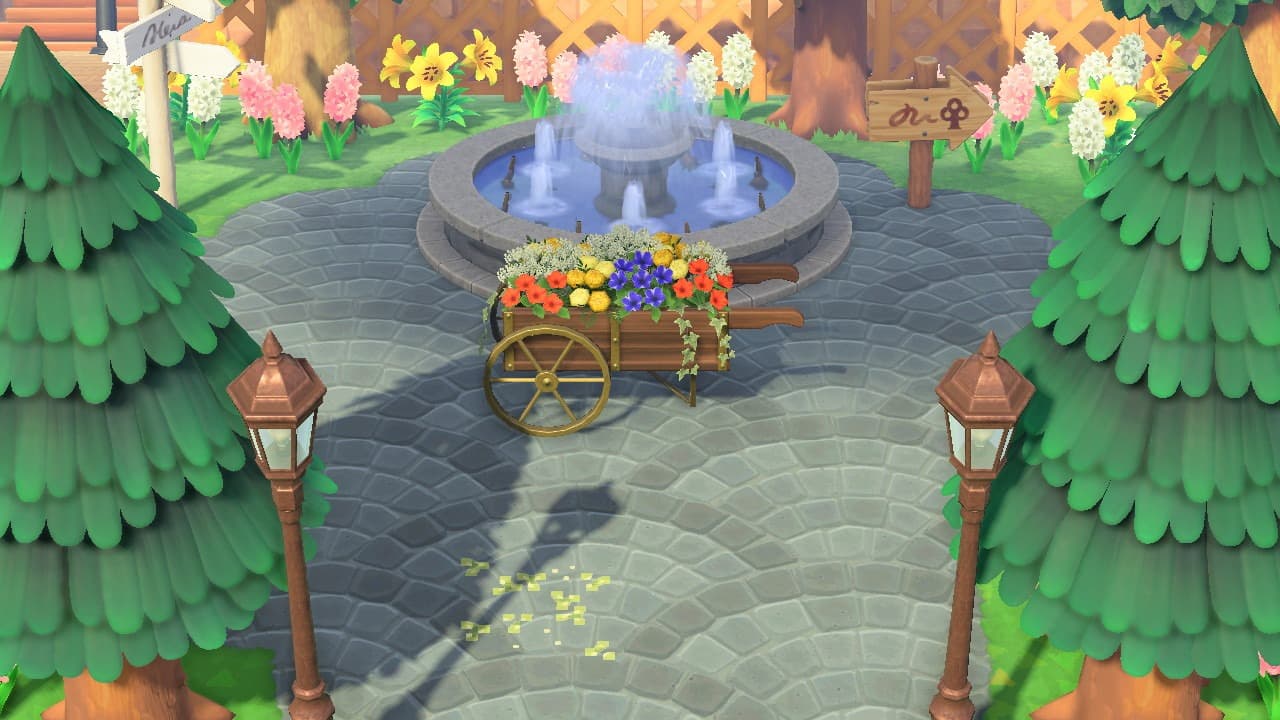 An image of part of an Animal Crossing Island layout featuring a fountain, trees, flowers and lamposts.