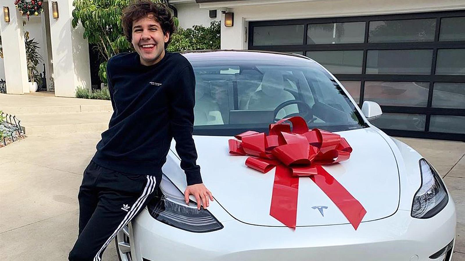 David Dobrik poses next to a Tesla with a bow on the hood.