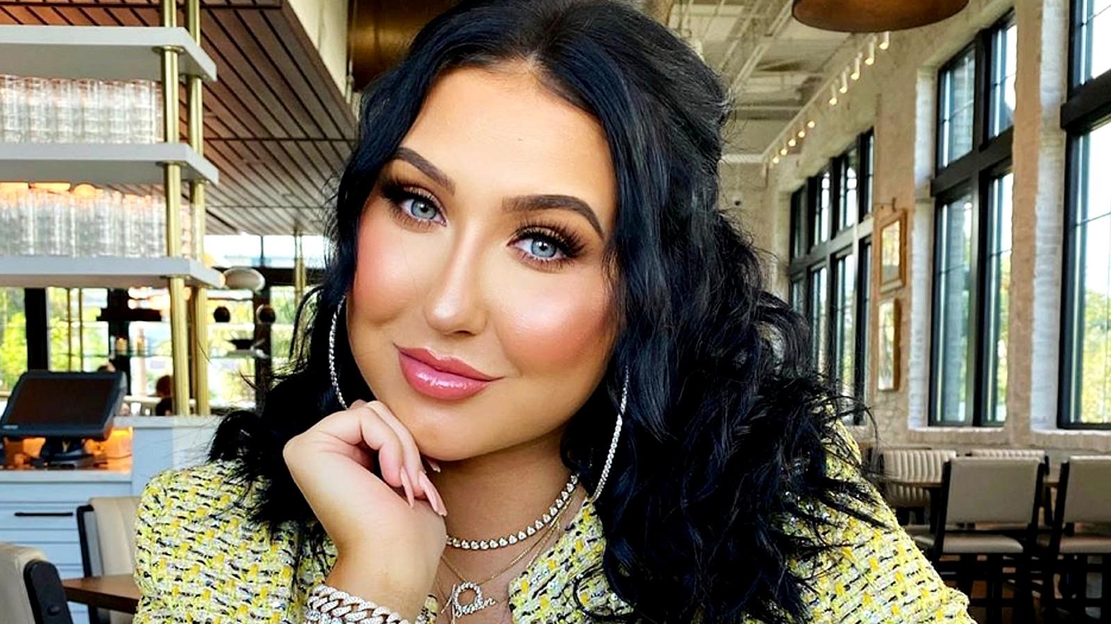 Jaclyn Hill poses with her head on her hand sitting down