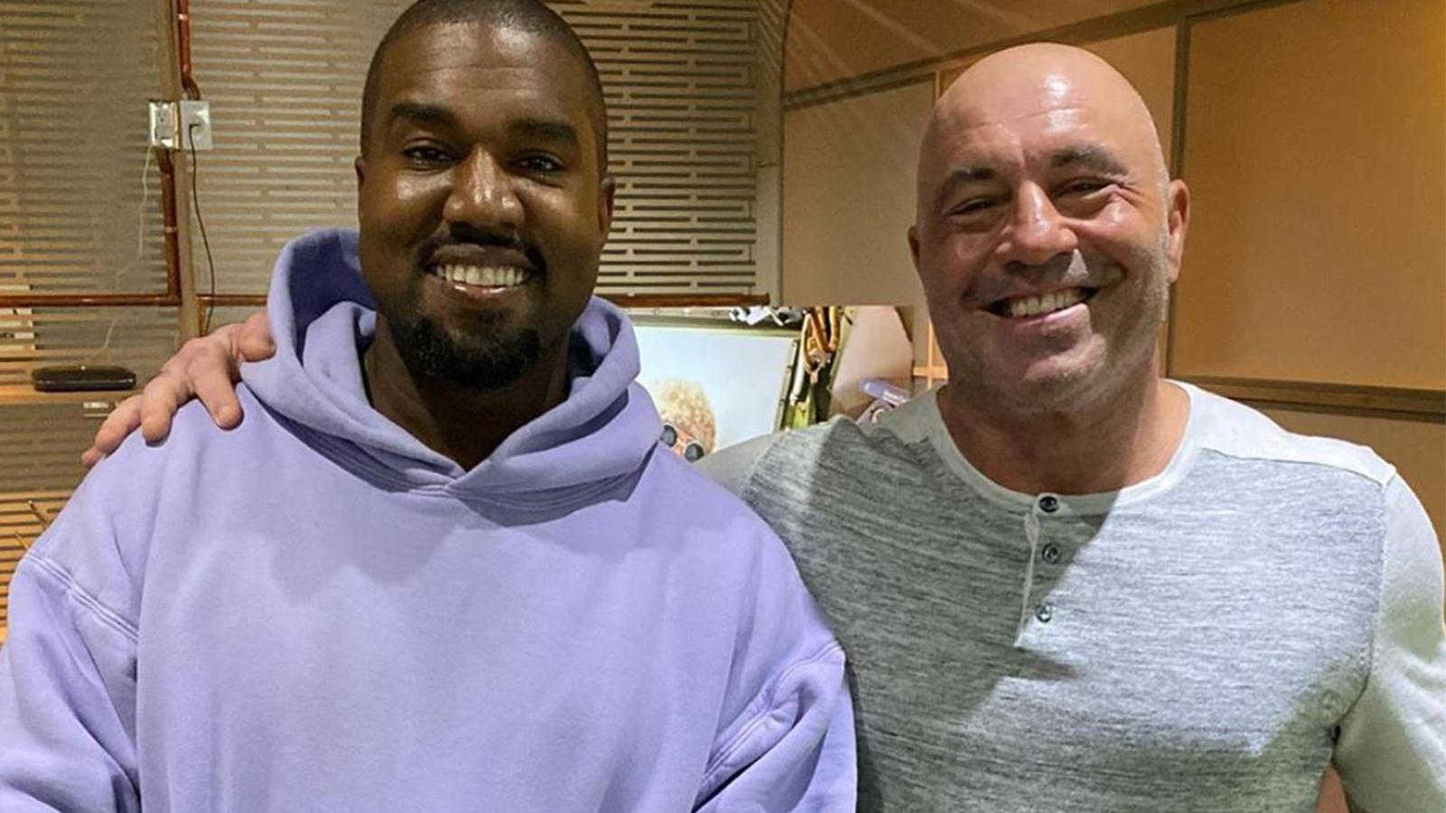 Joe Rogan and Kanye West embrace in a cheerful photo.