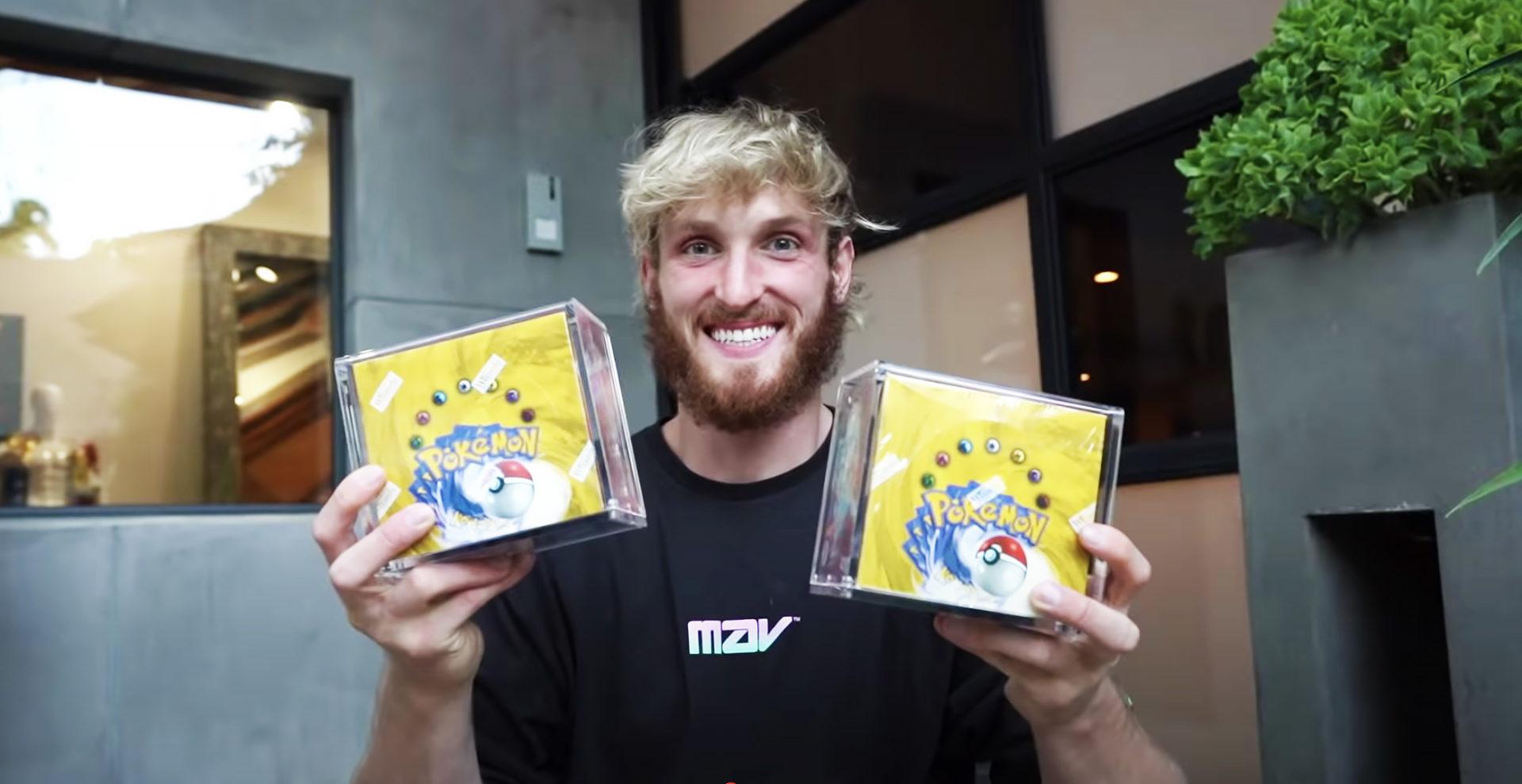 Logan Paul holds up pokemon card sets.