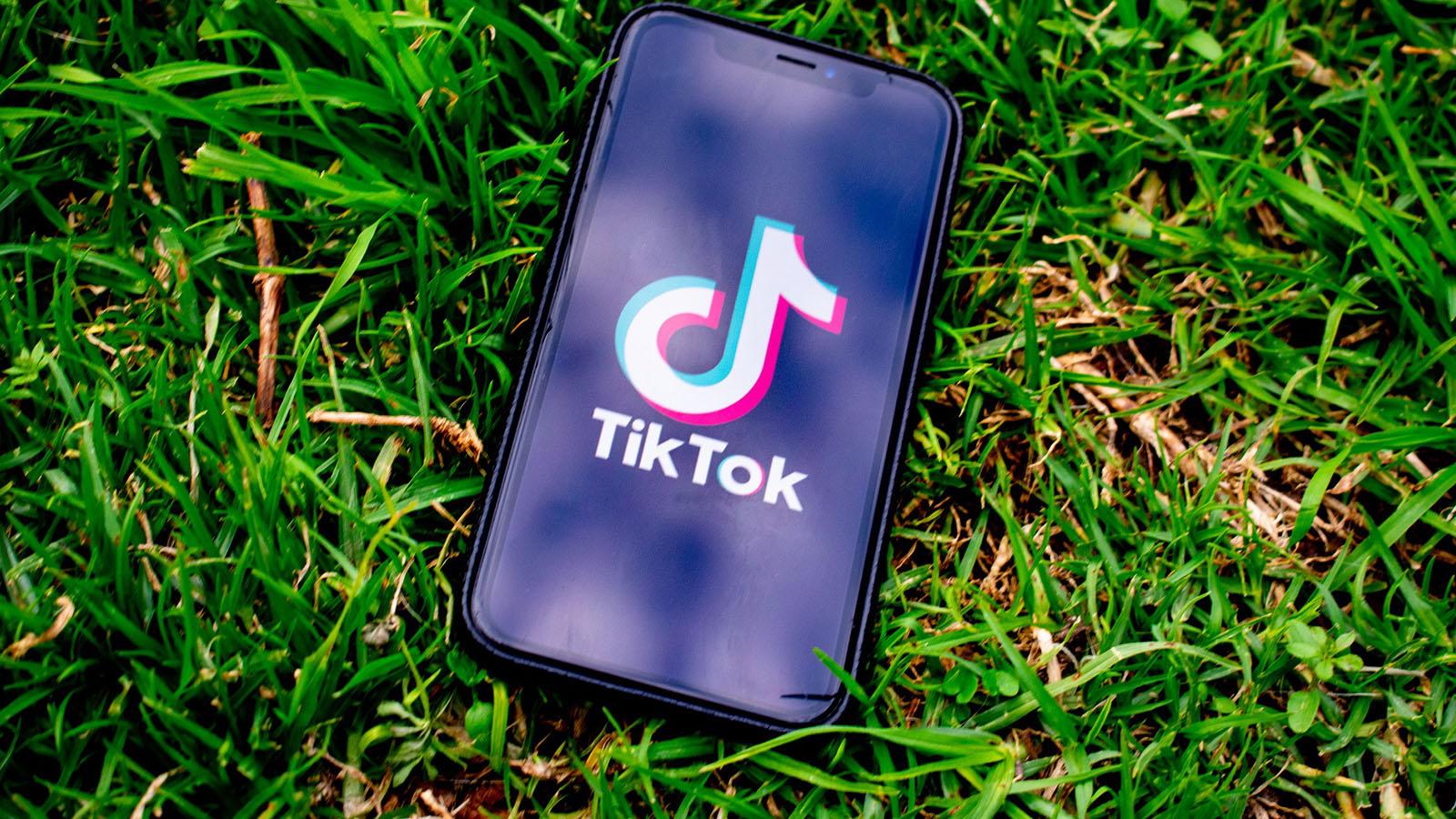 TIkTok on phone laying on grass