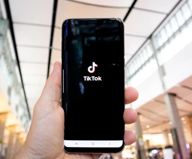 Person holding smartphone with TikTok on it.