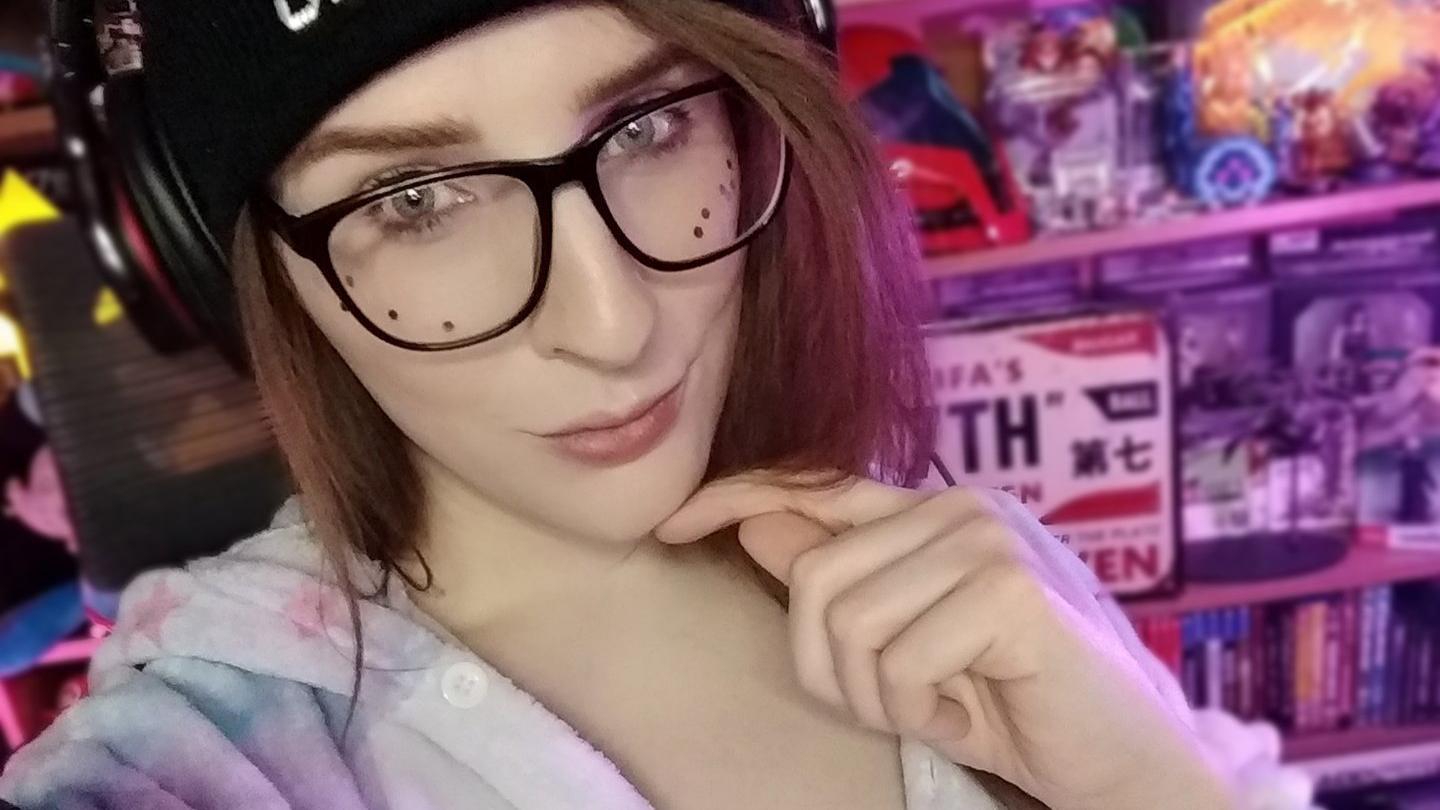 Miabyte, trans streamer on Twitch with glasses and a hat in her streaming setup.