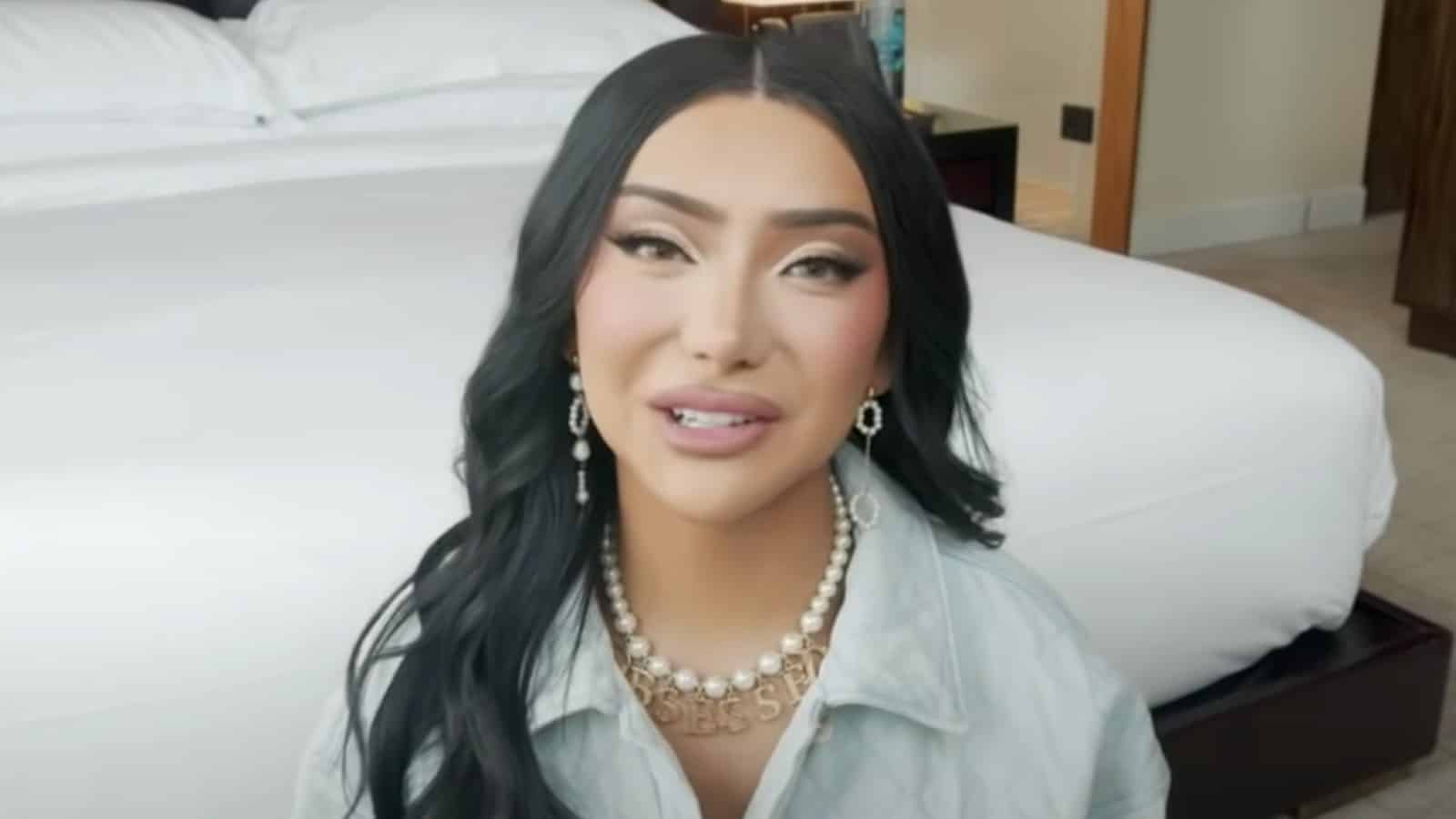 Nikita Dragun sitting on the floor in front of a bed