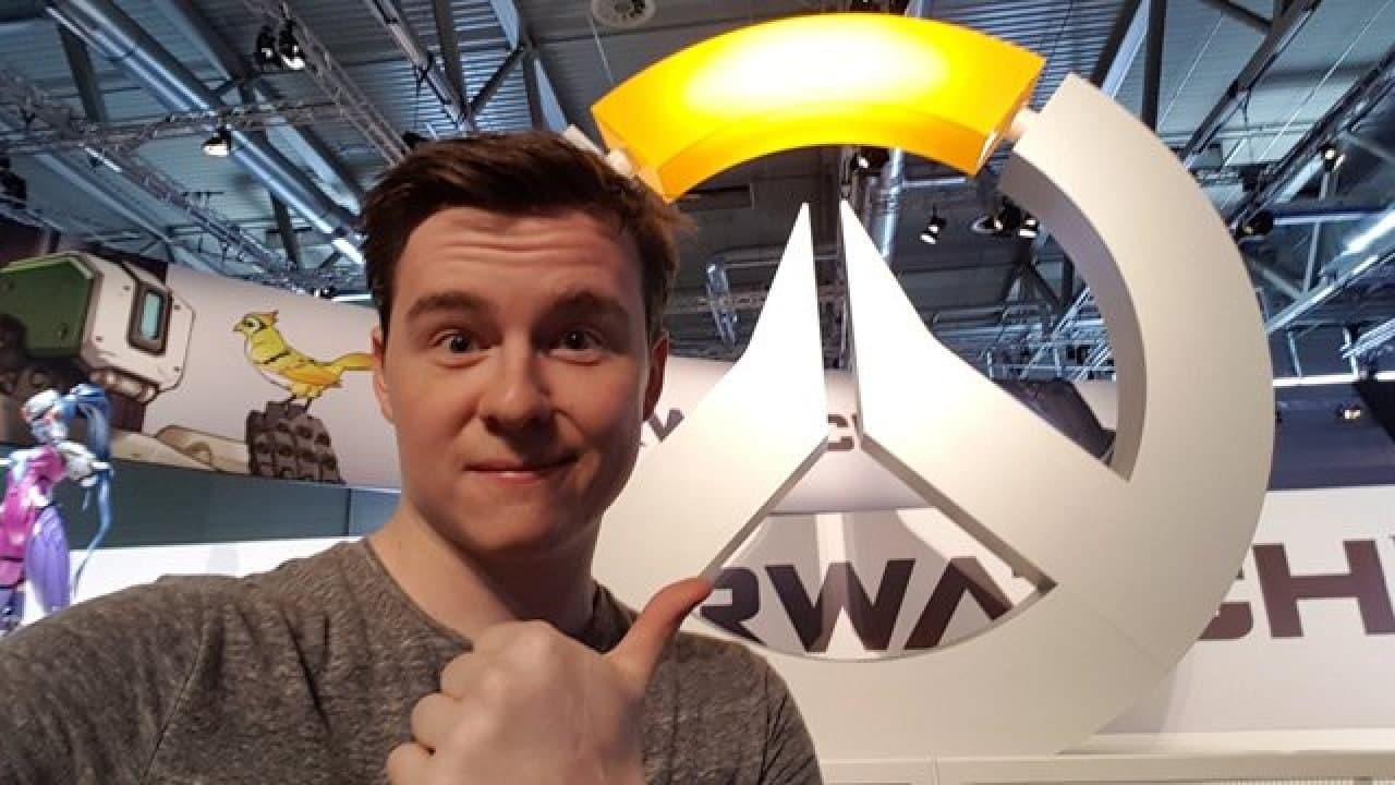 Muselk standing next to Overwatch logo