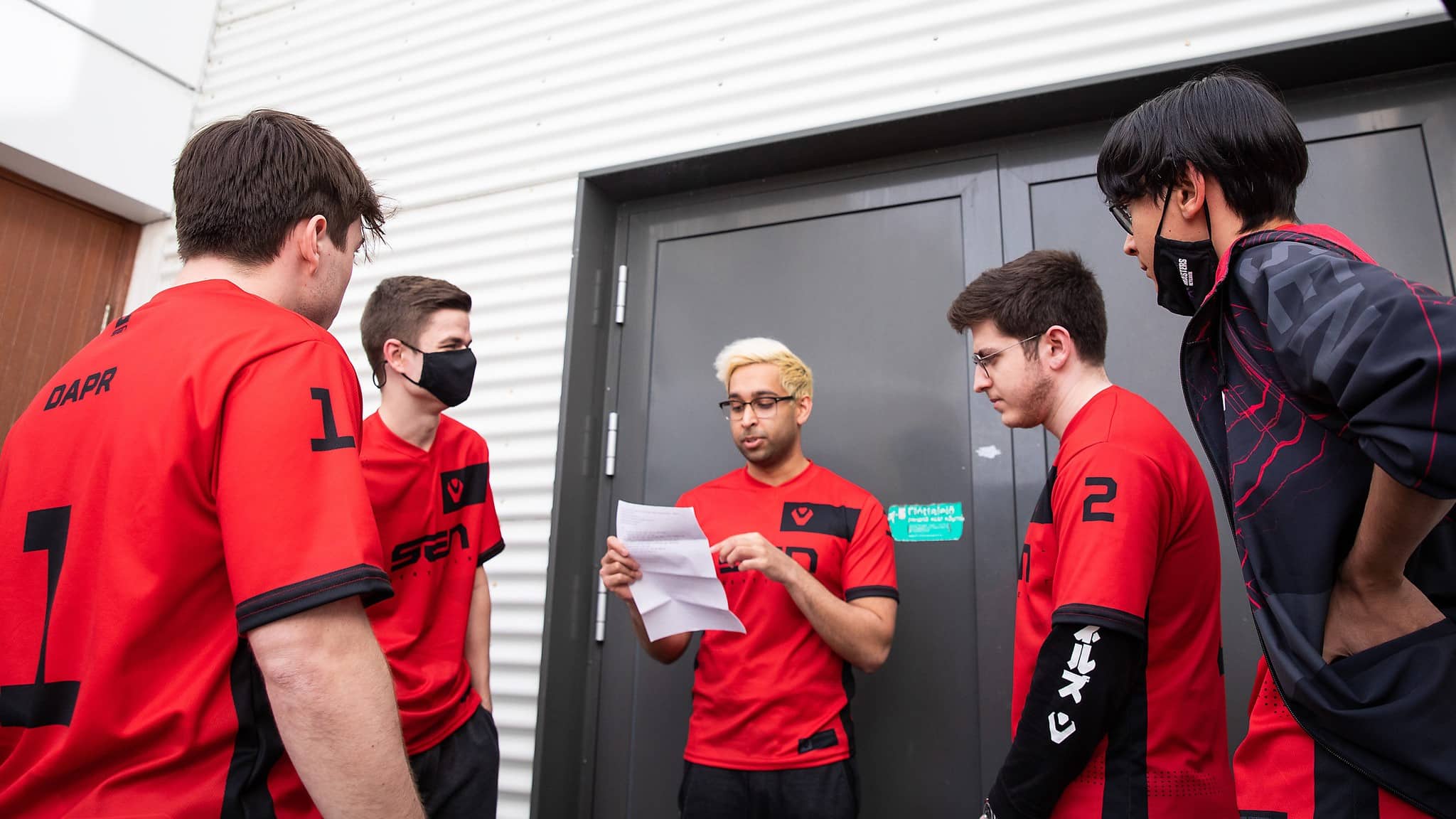 ShahZaM reading off a piece of paper surrounded by his Valorant teammates