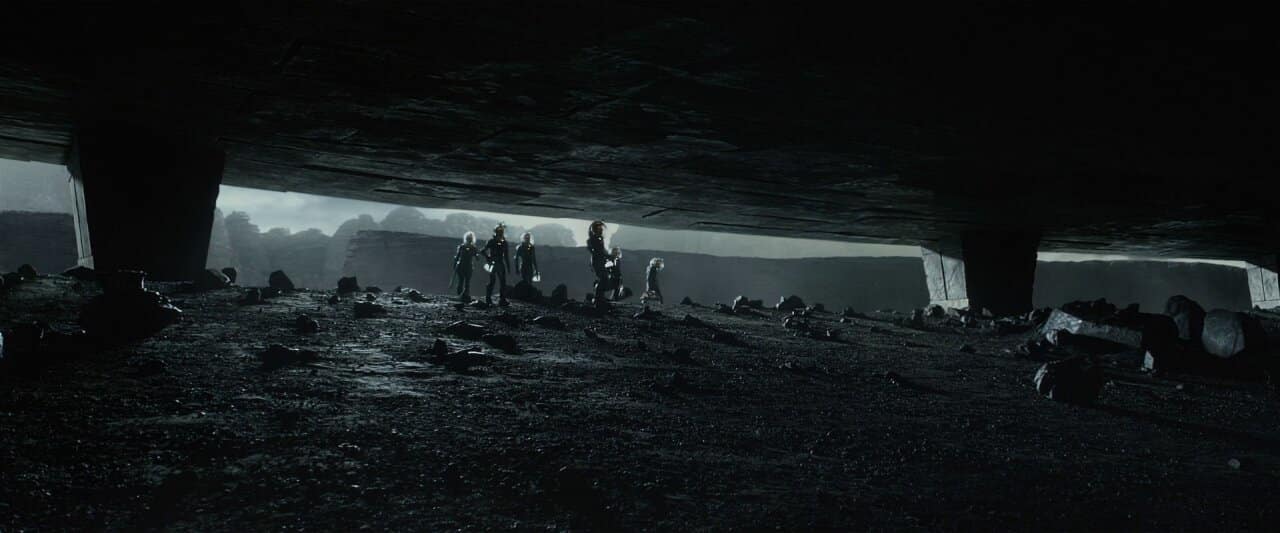 Space explorers walk along a dark rocky planet in Prometheus