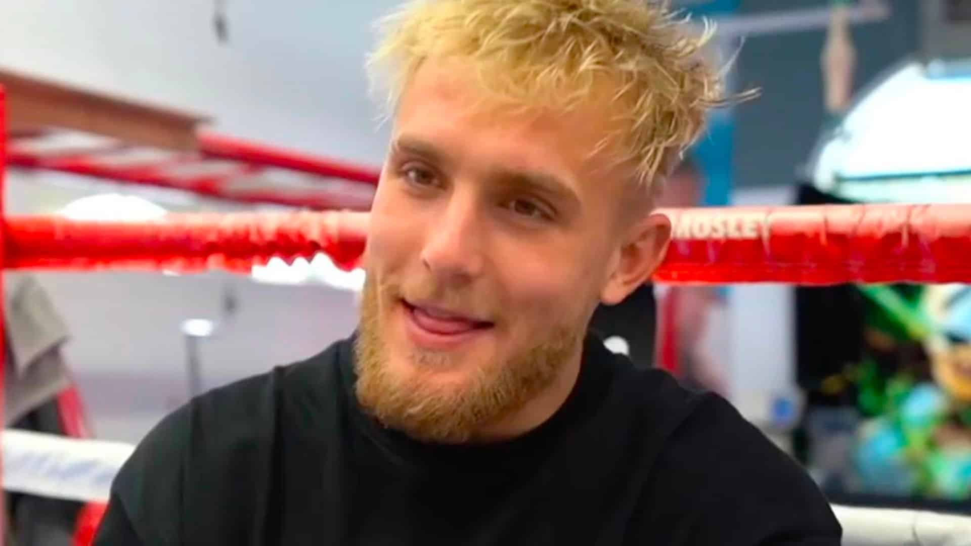Jake Paul smiling sitting on side of boxing ring