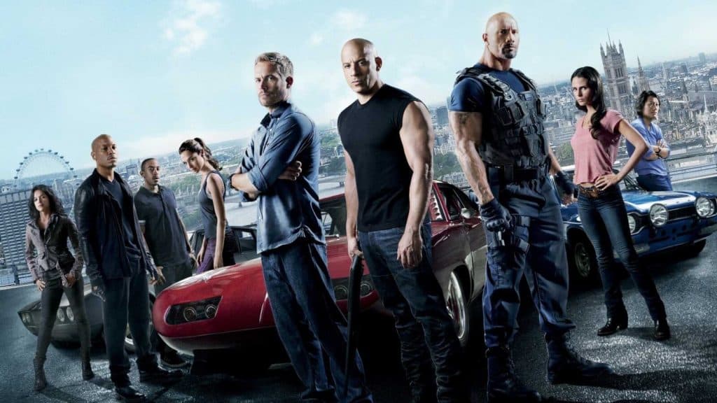 the cast of fast and furious stood next to cars
