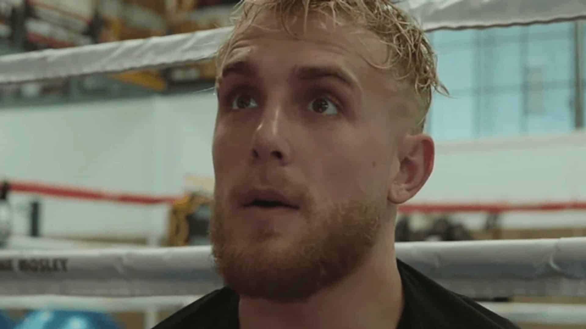 Jake Paul sat on boxing ring looking shcoked at camera