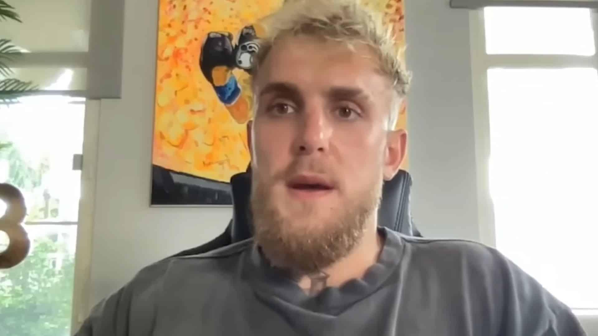 Jake Paul talking to camera with yellow and orange painting in background