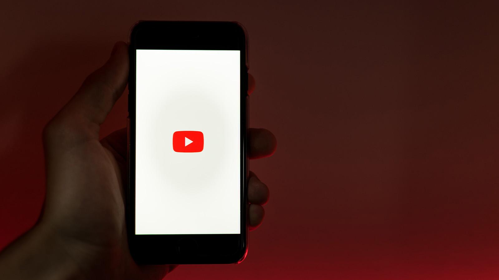 hand holding a phone with the YouTube logo on it