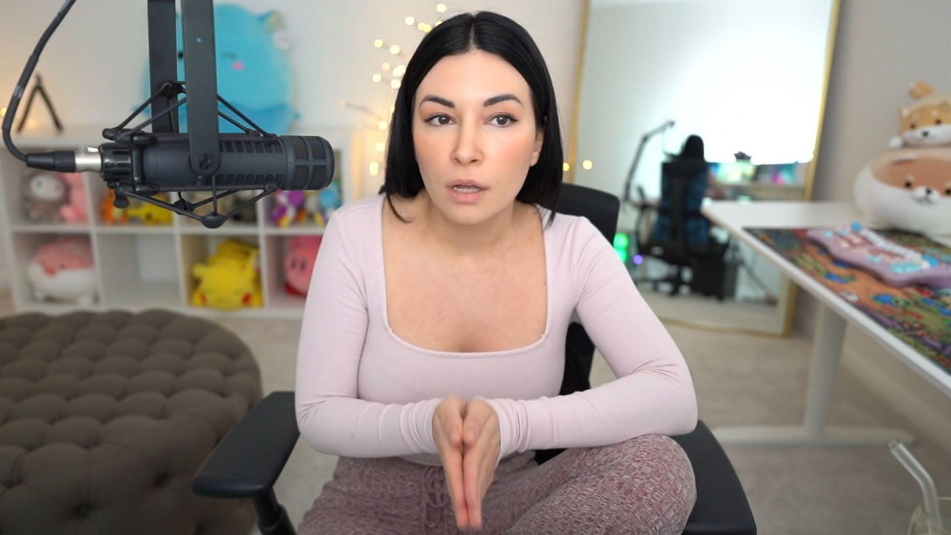 Alinity in pink shirt talking to camera and microphone