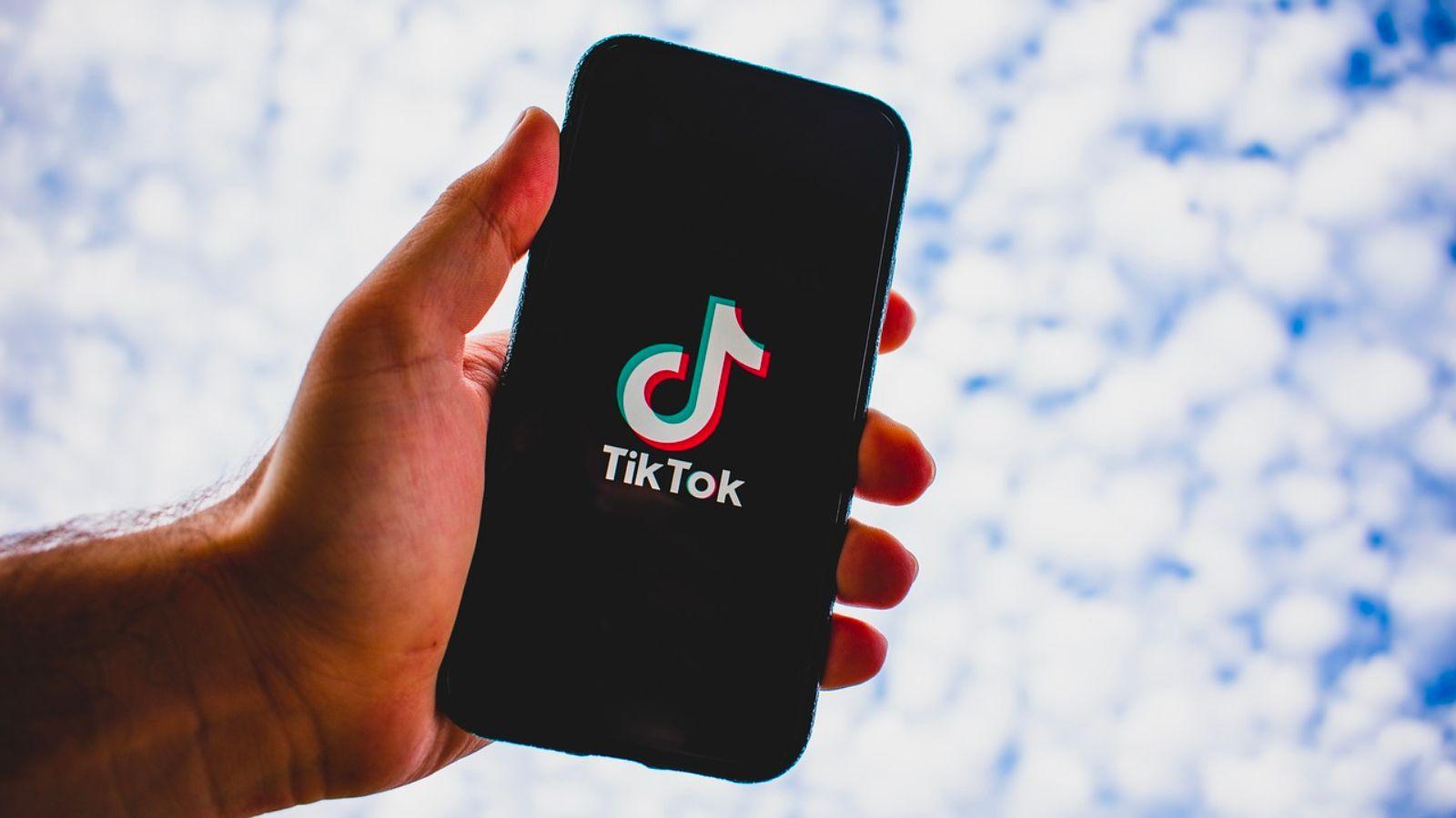 Hand holding smartphone with TikTok logo showing on screen