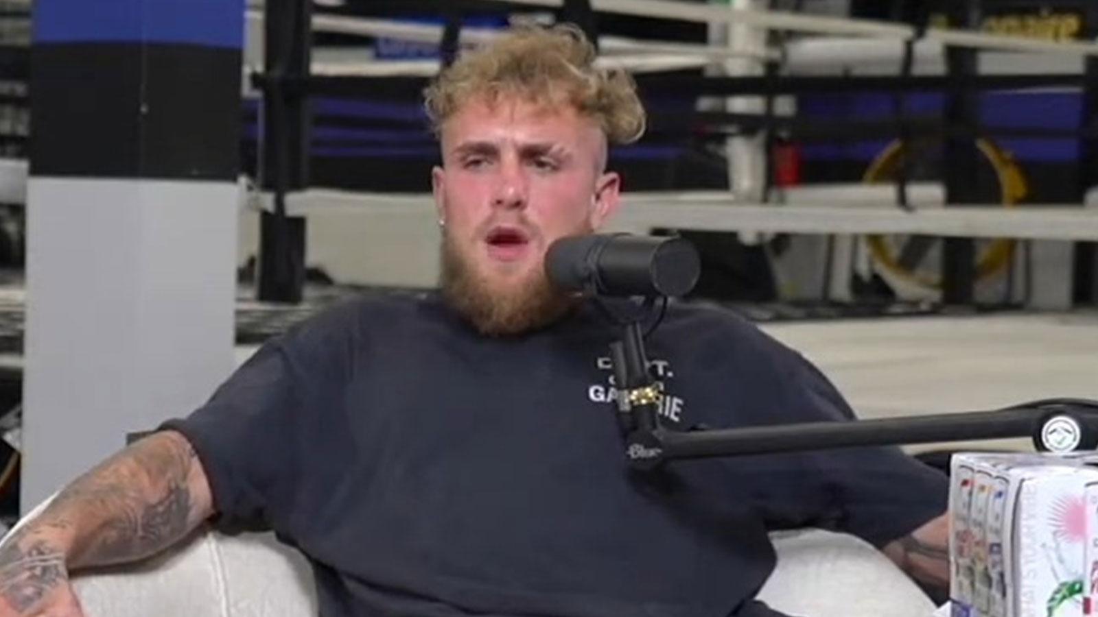 Jake Paul sat on chair wearing black t-shirt with microphone in front of face