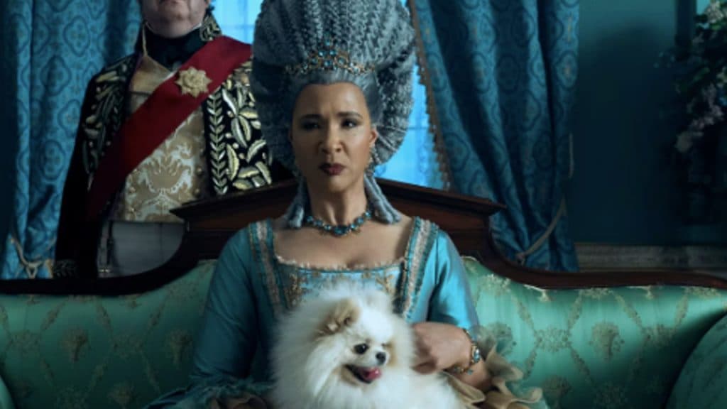 Older Queen Charlotte holds her dog in Queen Charlotte: A Bridgerton Story