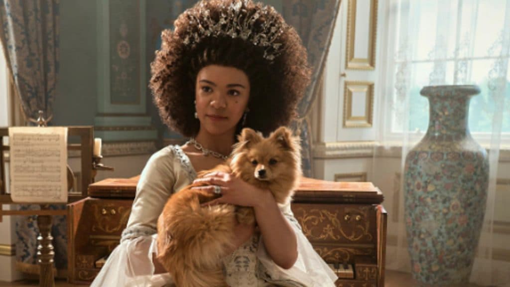 Young Queen Charlotte holds her dog in Queen Charlotte: A Bridgerton Story